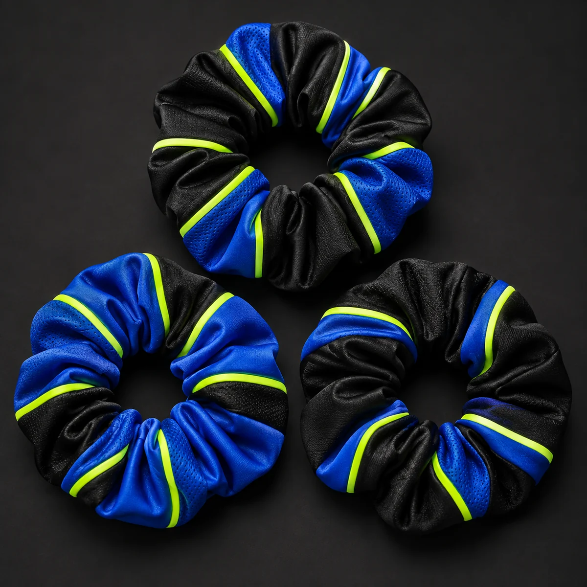 Three black, royal blue and volt custom team scrunchies.